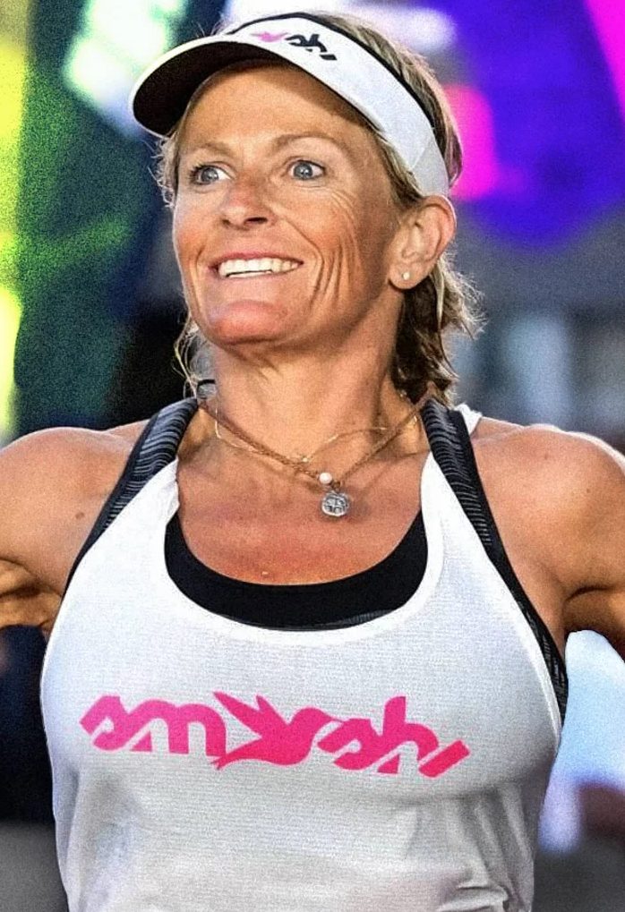 Erika Lilley smiling mid-race in a white tank top and visor